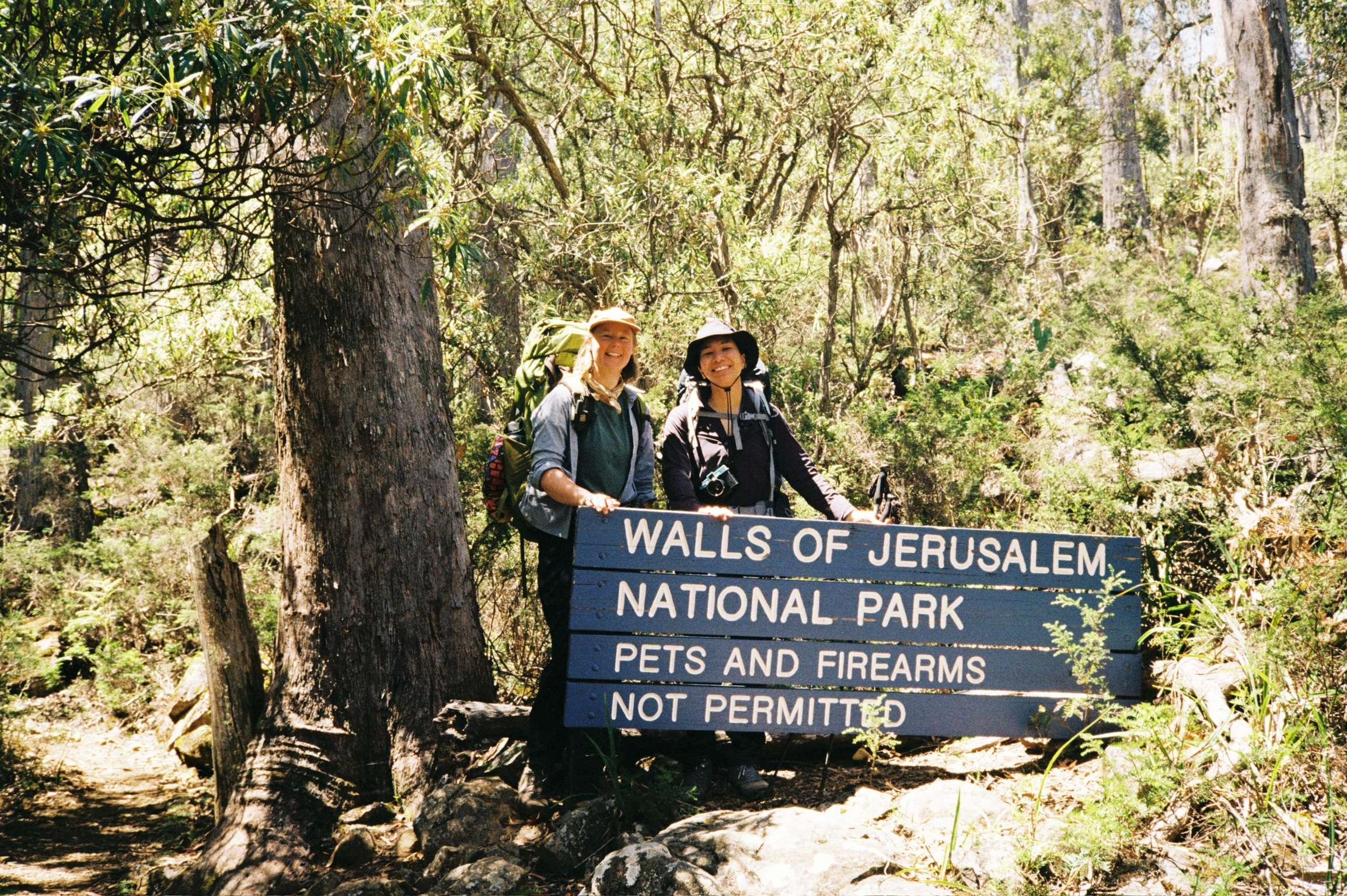 Amble Adventure Grant Winner Caz and her new friend Annisa smiling in front of the Walls of Jerusalem National Park signage