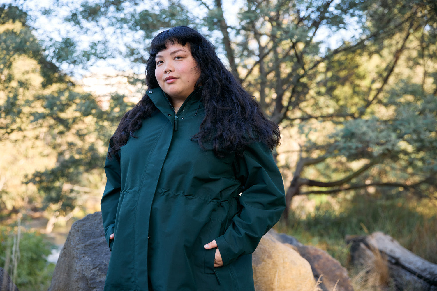 A model wearing the Overland Jacket in Eucalyptus with her hands in her pocket in nature