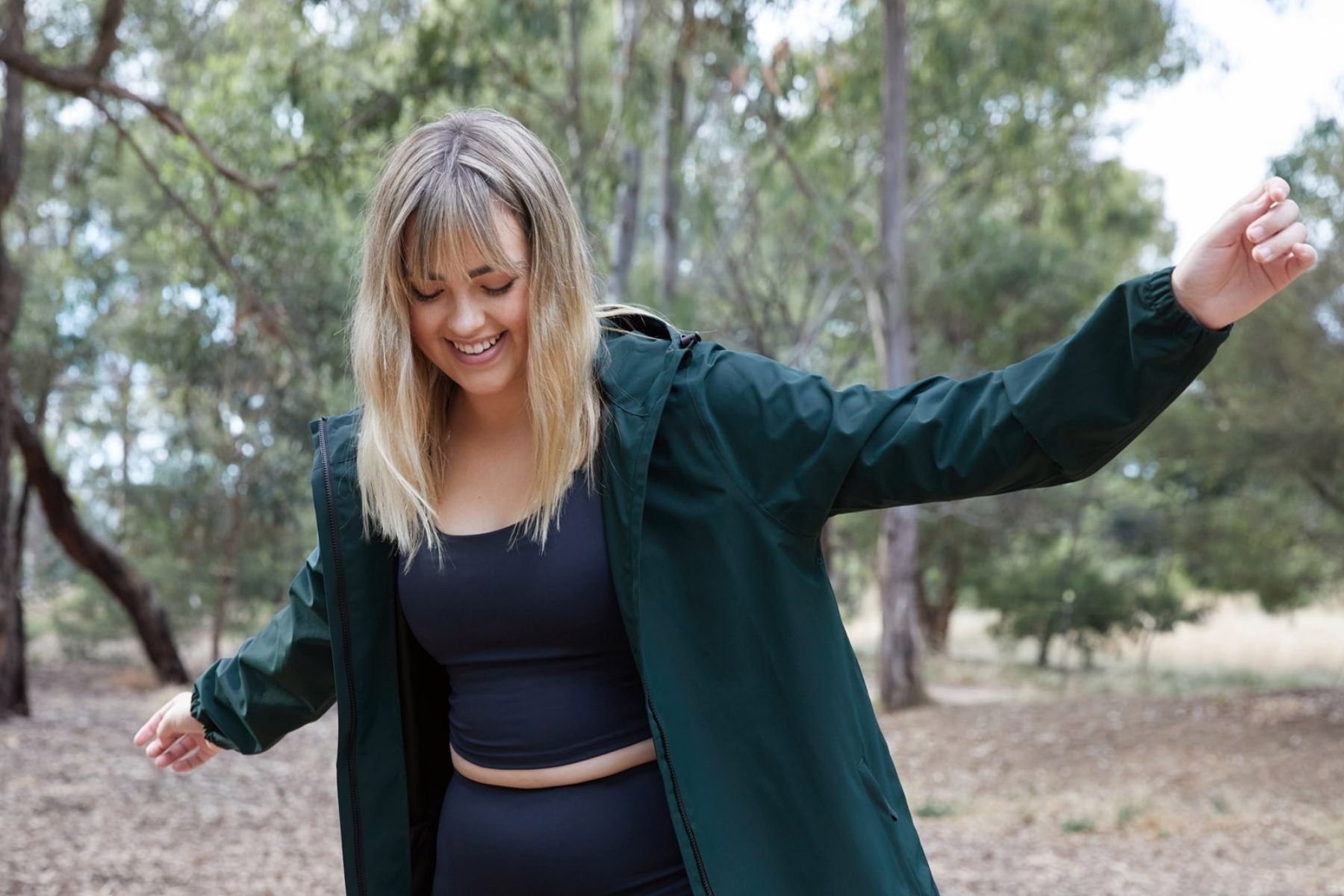 Smiling model in nature wearing the Amble Refuge Jacket in Eucalyptus